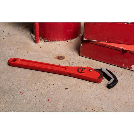 The Crescent CPW16S 16-inch steel pipe wrench resting on a concrete shop floor next to a red metal tool box, illustrating its durability in mechanical and industrial environments.
