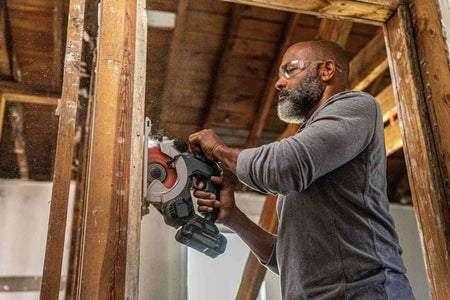 Action shot of a professional contractor using a cordless circular saw equipped with a Crescent NailSlicer blade to make a vertical plunge cut through a structural wooden stud.