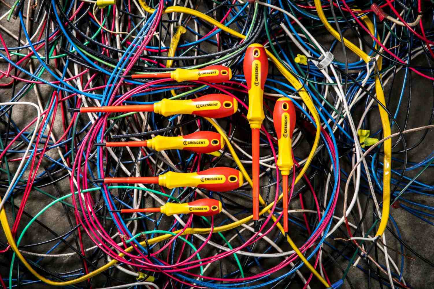 The complete Crescent 7-piece VDE insulated screwdriver set resting on top of a tangled pile of multi-colored electrical wires.