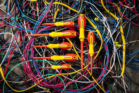 The complete Crescent 7-piece VDE insulated screwdriver set resting on top of a tangled pile of multi-colored electrical wires.