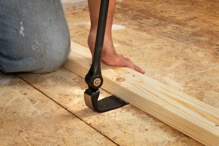Close-up of the Crescent indexing pry bar head positioned underneath a 2x4 wood stud, demonstrating the tool's ability to gain access and leverage in tight construction spaces.