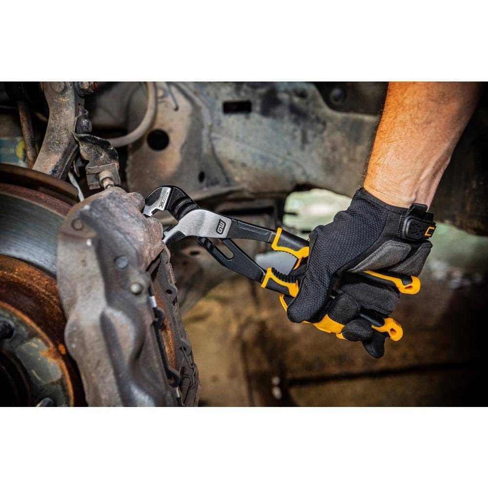An action shot of a mechanic in work gloves using the GearWrench 10-inch PITBULL K9 pliers to adjust a brake caliper on a vehicle, highlighting the tool's high-leverage design in automotive repair.