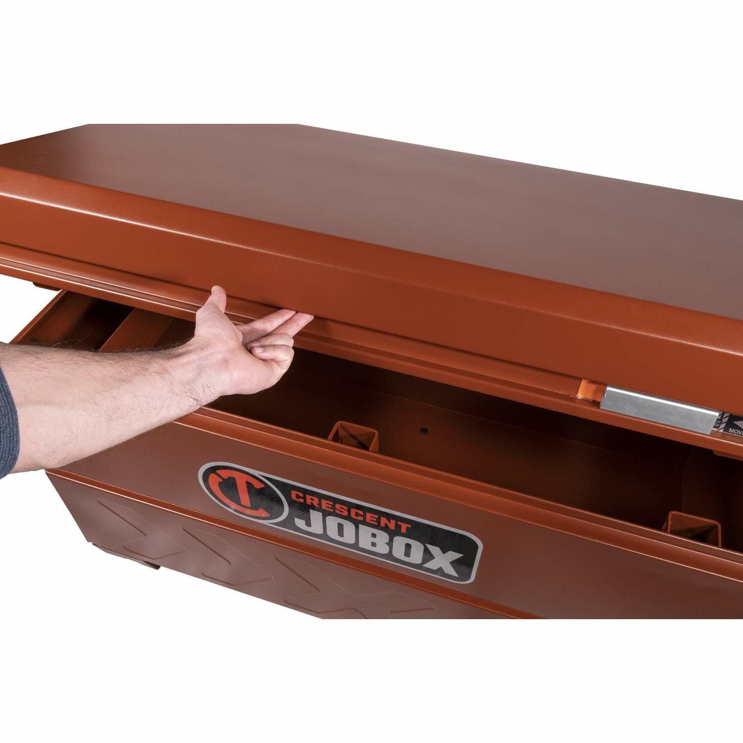 Person opening Crescent JOBOX chest using recessed handle under lid edge. Spacious interior visible. Branding displayed on front panel. Designed for secure tool storage in industrial or construction environments.