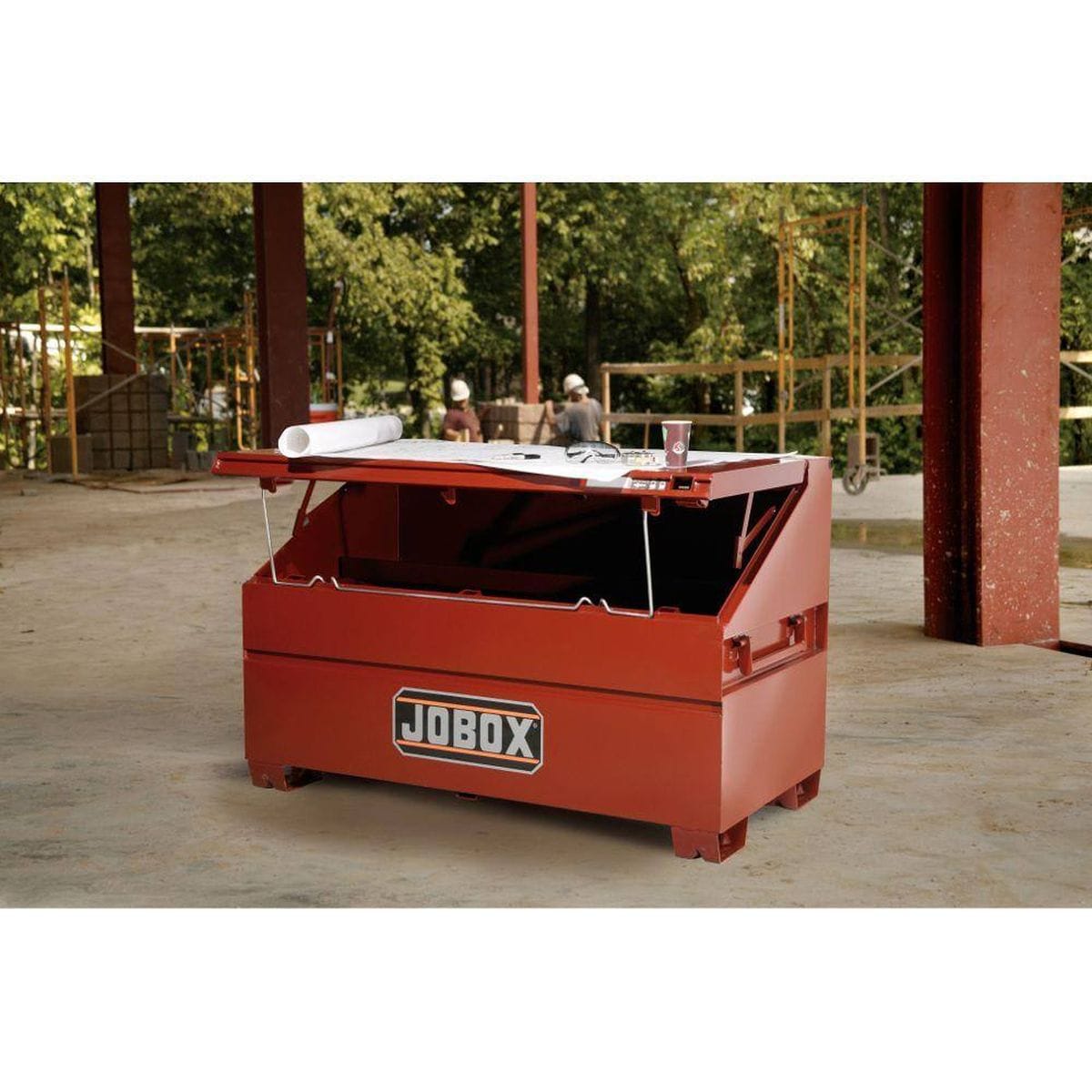 An action shot of the JOBOX 60-inch slope lid chest on an active construction site, showing the lid propped open to create a functional mobile workstation for reviewing blueprints and project plans.