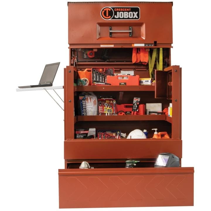 Crescent JOBOX 48-inch Site-Vault heavy-duty piano box jobsite storage cabinet, shown open from the front. Interior shelves are filled with tools, and a laptop is on the extended side shelf. The bottom drawer is open.