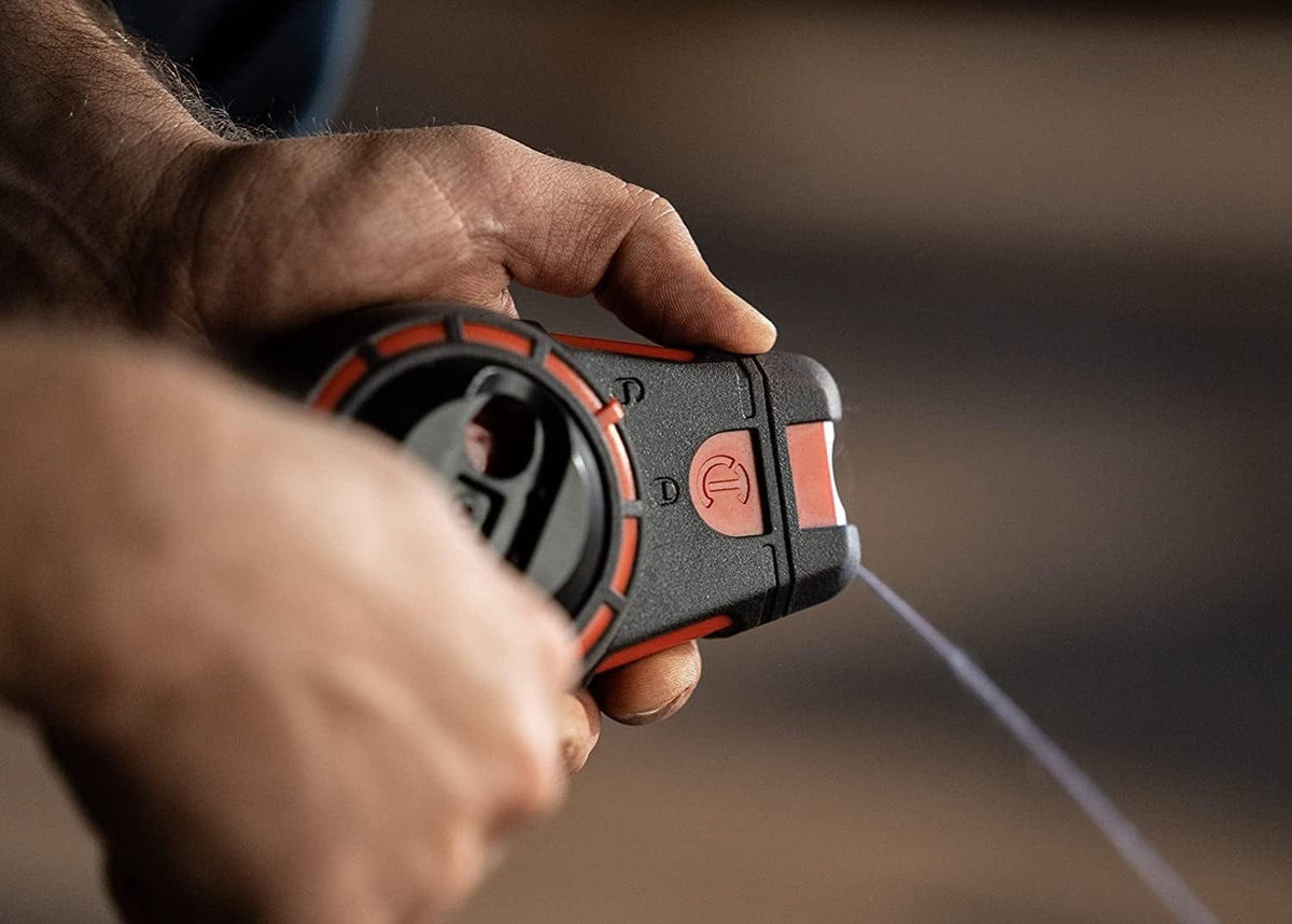 Worker using the Crescent Lufkin chalk reel to pull a 100-foot braided line for an indoor layout, highlighting the ease of professional one-handed operation.