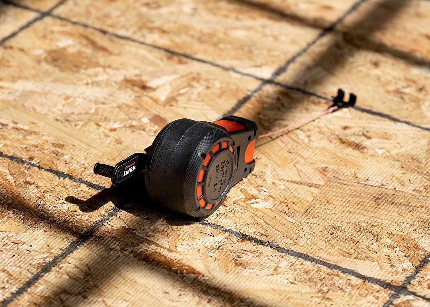 Crescent Lufkin CL100B chalk reel resting on a plywood subfloor with the 100-foot line deployed for horizontal marking during a framing layout.