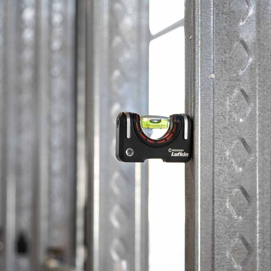 The Crescent Lufkin pocket level is shown magnetically attached vertically to a metal stud, with the bubble centered to show plumb.