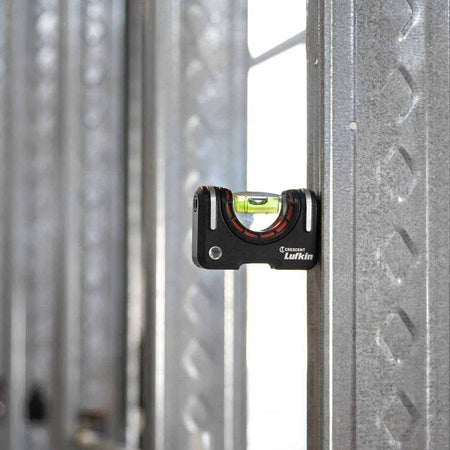 The Crescent Lufkin pocket level is shown magnetically attached vertically to a metal stud, with the bubble centered to show plumb.
