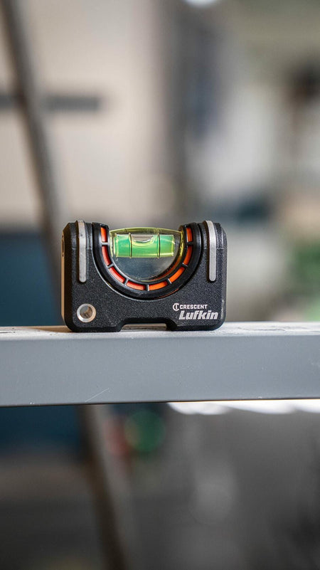 The Crescent Lufkin pocket level is shown resting horizontally on a gray metal beam, with the magnified vial bubble centered.