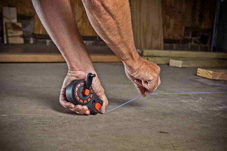 Person using a tape measure on a wooden floor