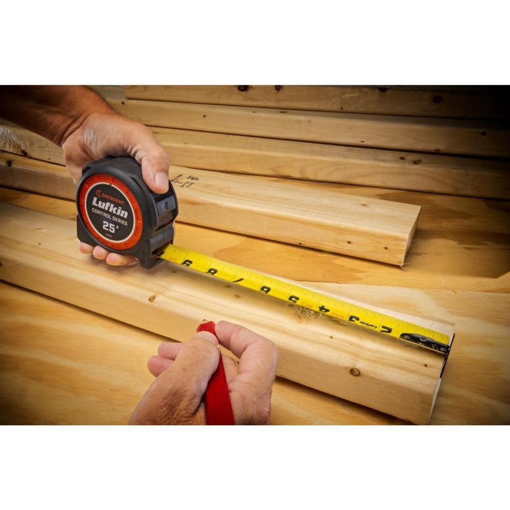 A tradesperson using the Crescent Lufkin Command Control 26' tape measure to mark a piece of dimensional lumber, demonstrating the 1-3/16 inch wide blade's stability and high-legibility print for precision layout work.