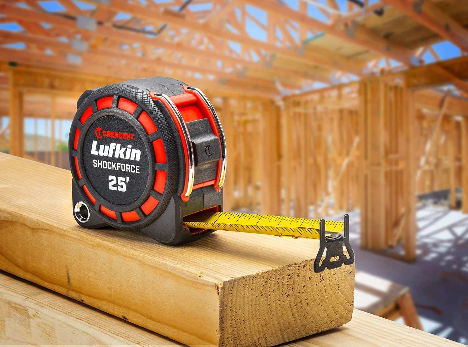 An action photograph of a professional using the Crescent Lufkin Shockforce G1 tape measure to measure a steel beam, demonstrating the versatility of the 360-degree end hook for industrial layout tasks.