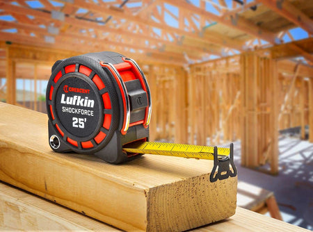 An action photograph of a professional using the Crescent Lufkin Shockforce G1 tape measure to measure a steel beam, demonstrating the versatility of the 360-degree end hook for industrial layout tasks.