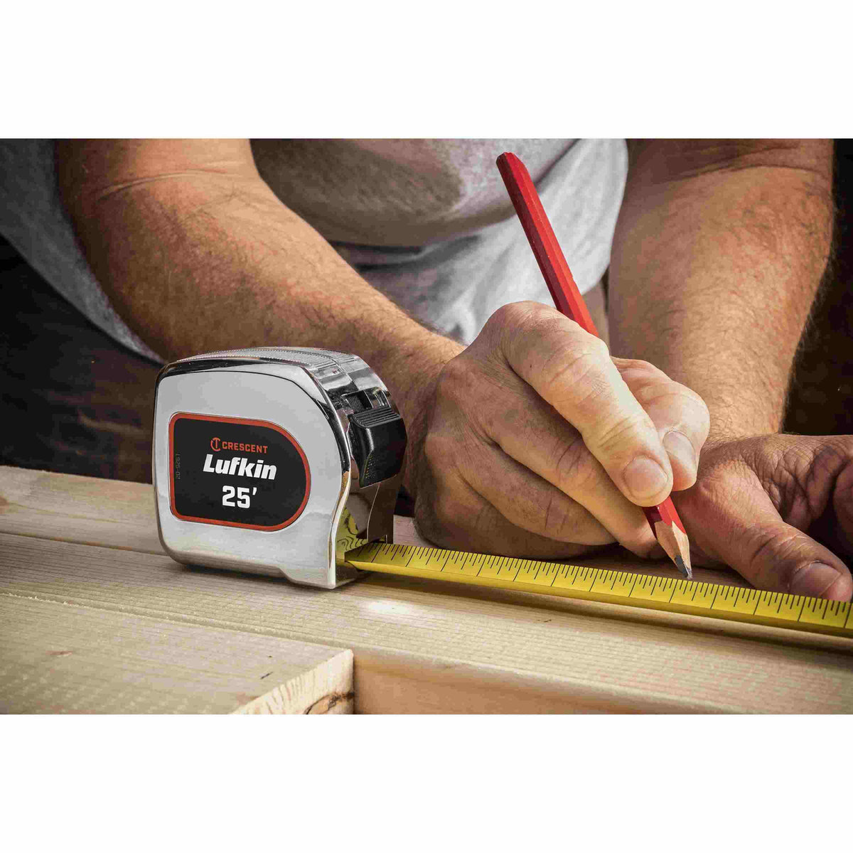 A professional contractor using the Crescent Lufkin L925-02 tape measure and a pencil to mark a precise measurement on a piece of lumber on a job site.