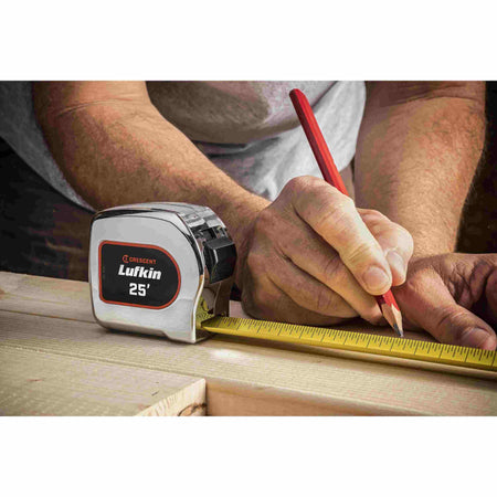A professional contractor using the Crescent Lufkin L925-02 tape measure and a pencil to mark a precise measurement on a piece of lumber on a job site.