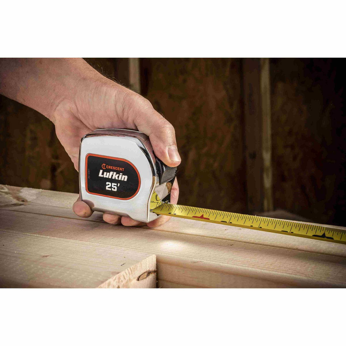 A user utilizing the Crescent Lufkin 25-foot chrome tape measure to check the dimensions of a structural wooden beam during an indoor construction project.