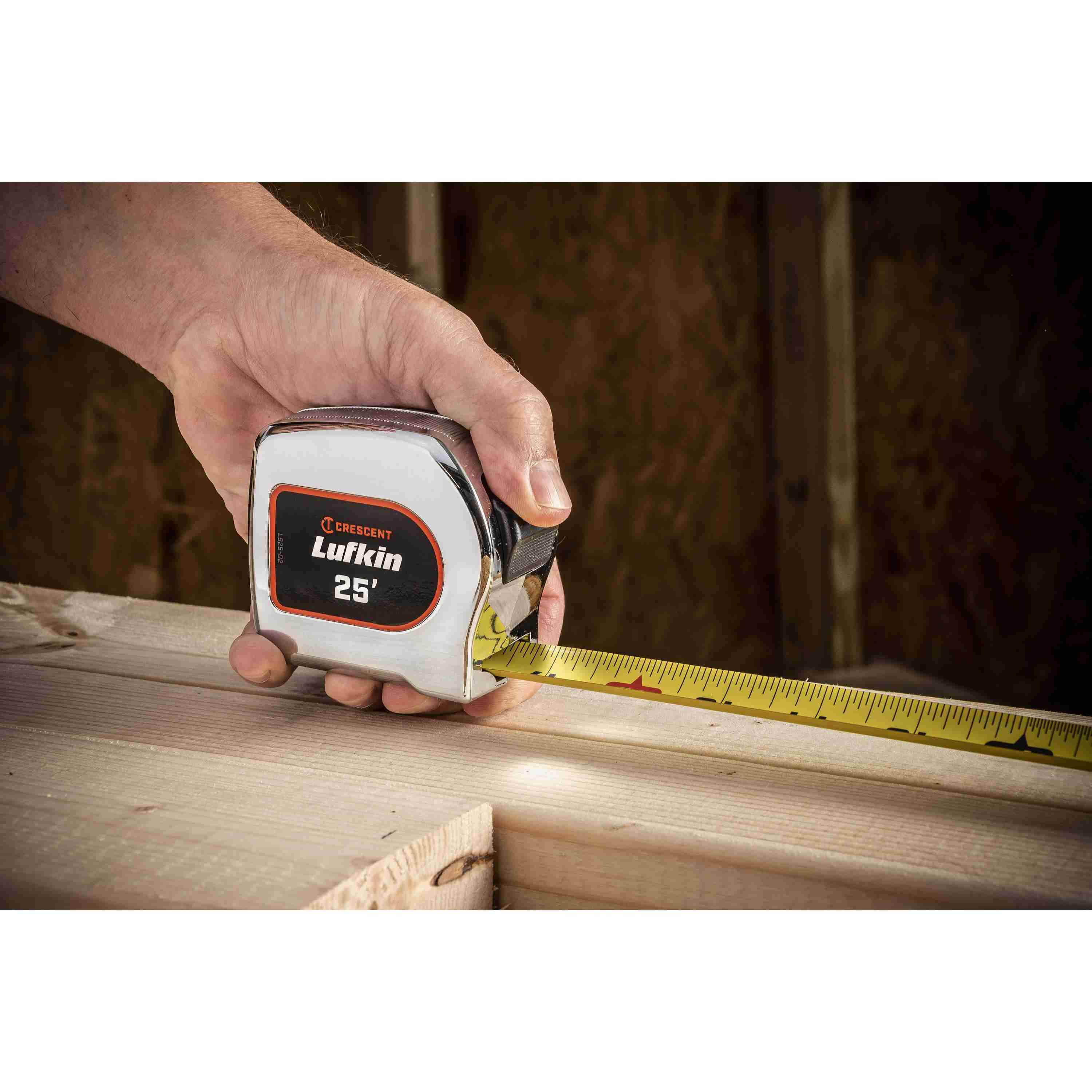 A user utilizing the Crescent Lufkin 25-foot chrome tape measure to check the dimensions of a structural wooden beam during an indoor construction project.