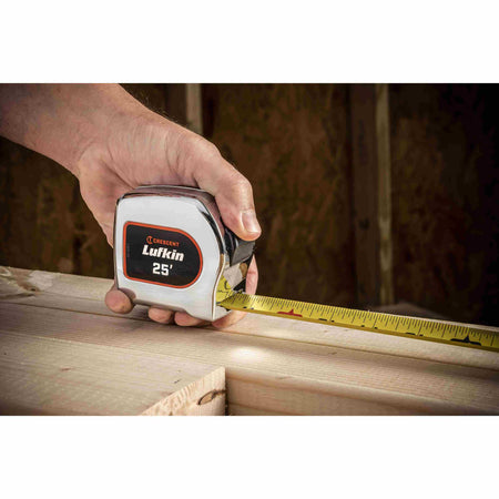 A user utilizing the Crescent Lufkin 25-foot chrome tape measure to check the dimensions of a structural wooden beam during an indoor construction project.