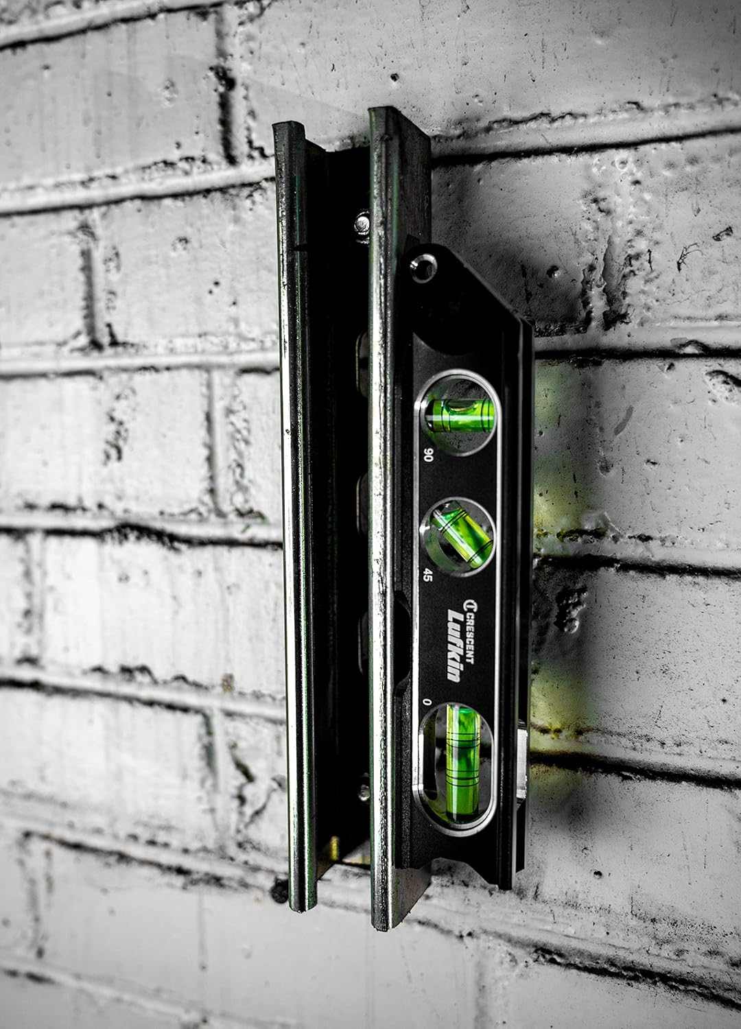 An action photograph of the Crescent Lufkin LBL1100-02 billet level magnetically attached to a vertical steel channel, showcasing the superior holding power of the rare earth magnets for hands-free professional measuring.