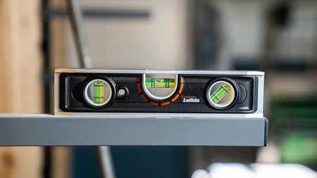 A detailed action shot of the Crescent Lufkin LTLA1100-02 torpedo level resting on a horizontal grey metal beam, emphasizing its accuracy and reliability for precision layout and installation tasks.