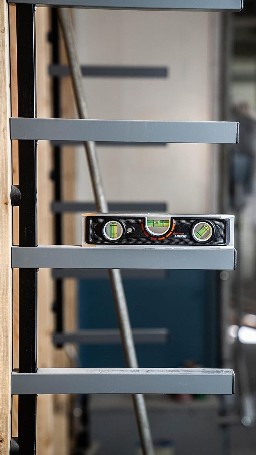 Action shot showing the Crescent Lufkin torpedo level being used to verify the horizontal alignment of a grey metal racking system, illustrating its accuracy and utility in commercial and industrial installations.