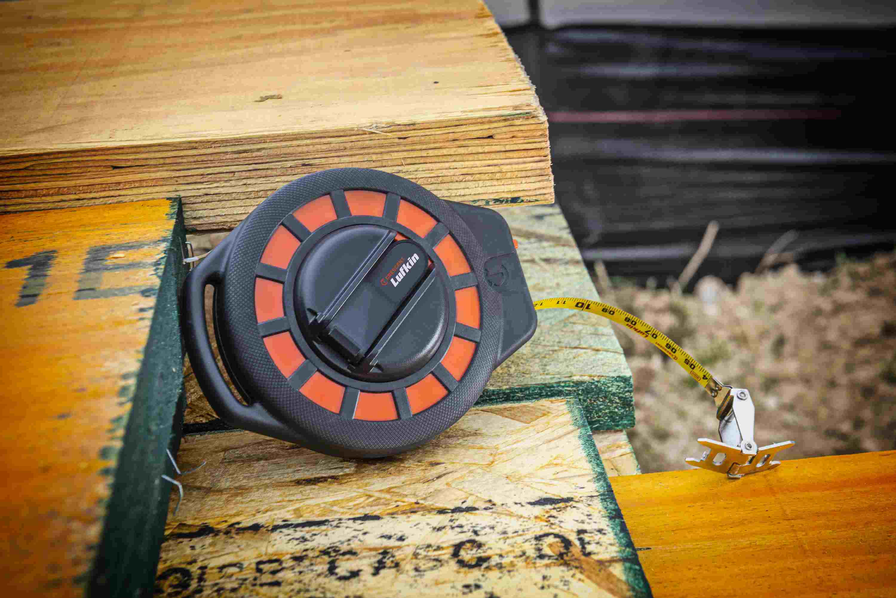 A detailed shot of the Crescent Lufkin ST50-07 resting on wooden framing, emphasizing the high-visibility yellow steel blade with dual SAE and Metric markings for professional accuracy.