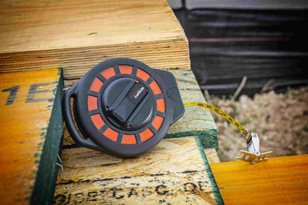 A detailed shot of the Crescent Lufkin ST50-07 resting on wooden framing, emphasizing the high-visibility yellow steel blade with dual SAE and Metric markings for professional accuracy.