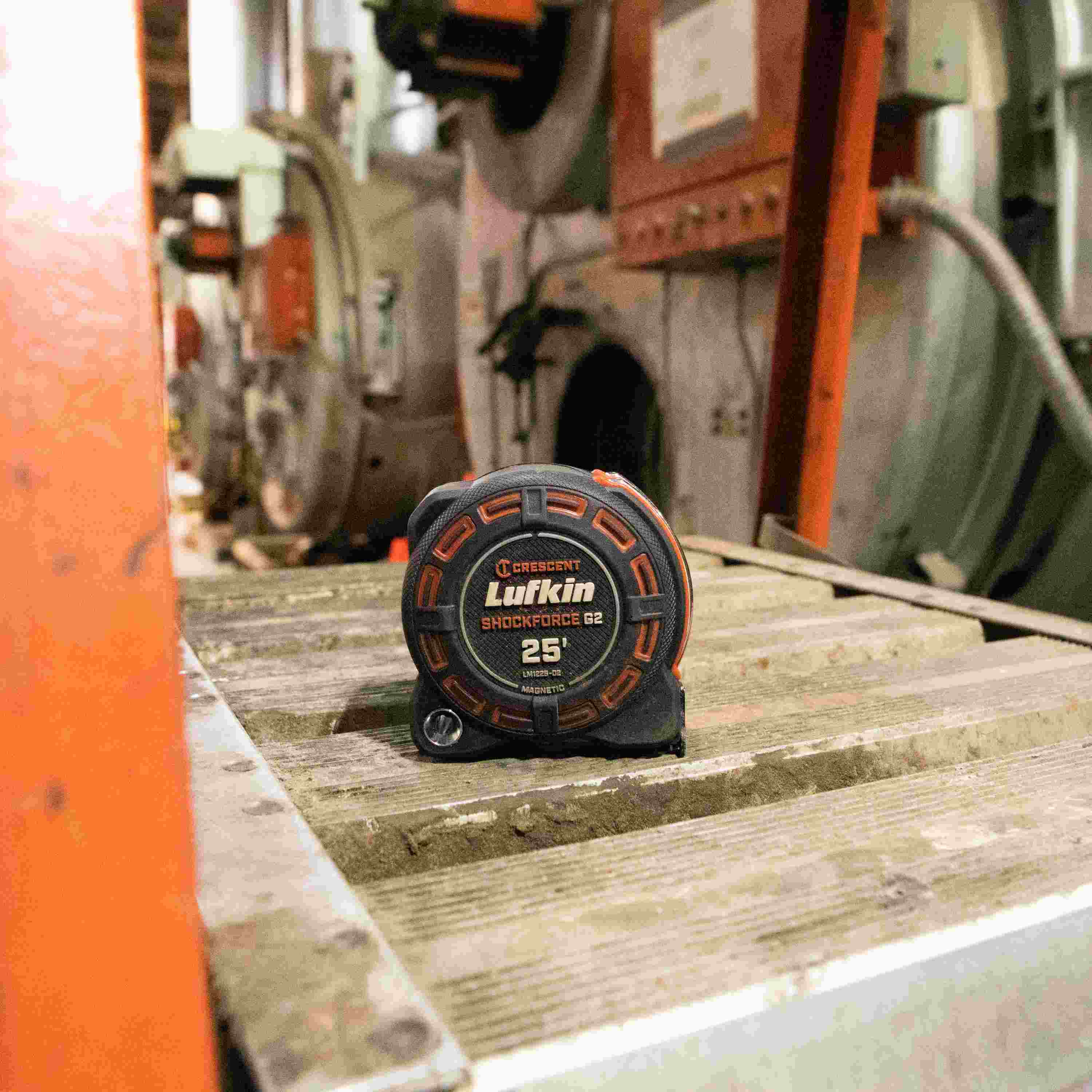A Crescent Lufkin Shockforce G2 25-foot tape measure resting on an industrial metal surface, highlighting its rugged build and visibility in a professional work environment.