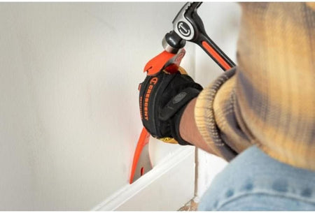 Action shot of a worker using a hammer to strike the integrated striking surface of the Crescent 12-inch molding bar to drive the precision edge behind a white baseboard.