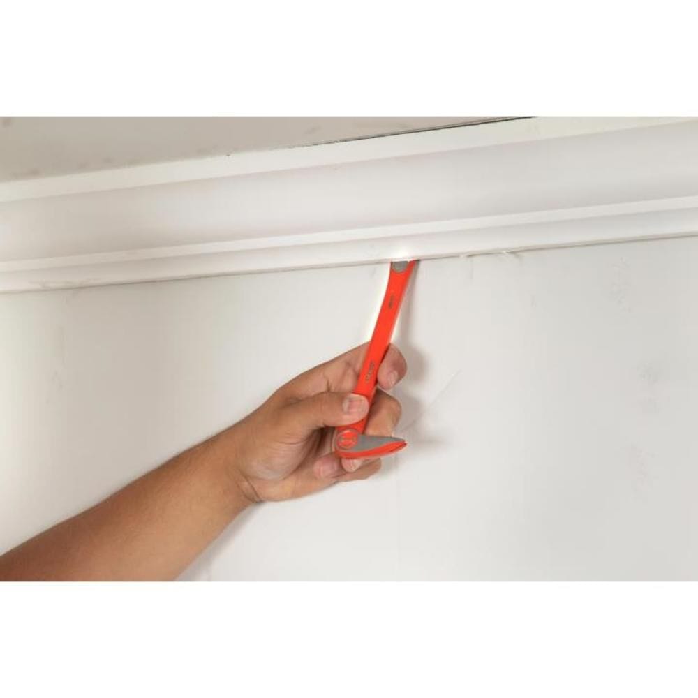 Close-up shot of a person using the Crescent molding pry bar to carefully remove white crown molding from a ceiling, demonstrating the tool's effectiveness in tight renovation spaces.