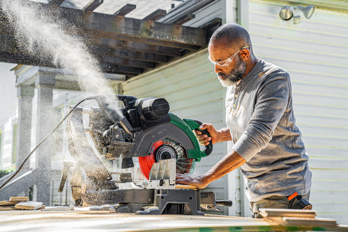Carpenter using a Crescent 12-inch 80-tooth saw blade on a sliding compound miter saw to make clean trim cuts.