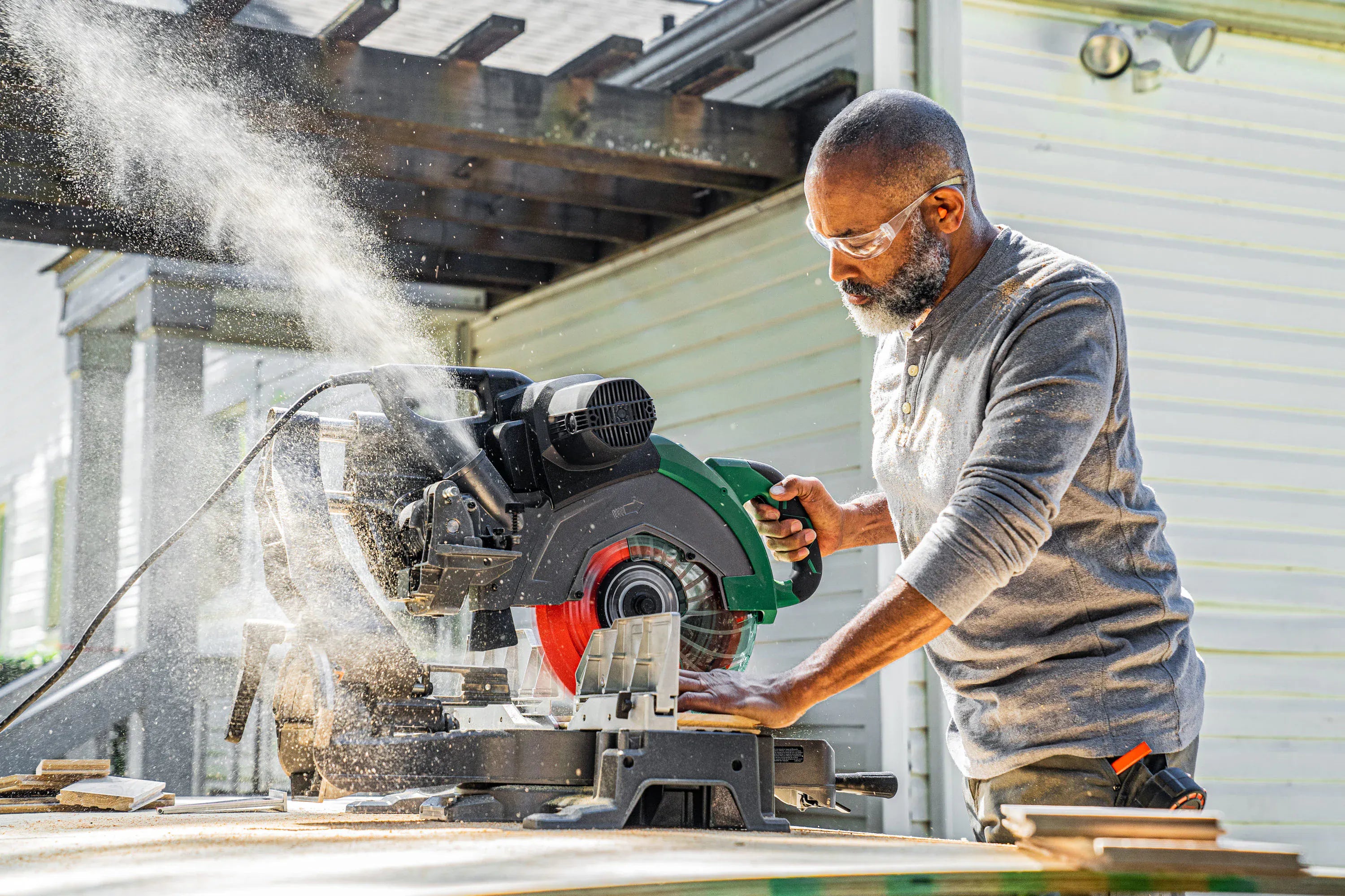 Carpenter using a Crescent 12-inch 80-tooth saw blade on a sliding compound miter saw to make clean trim cuts.