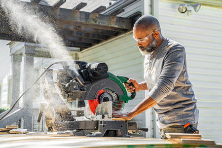 Carpenter using a Crescent 12-inch 80-tooth saw blade on a sliding compound miter saw to make clean trim cuts.