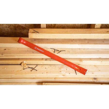 The Crescent PB18 18-inch I-beam steel wrecking pry bar resting on a stack of lumber at a job site, highlighting its durable Hi-Viz orange finish.