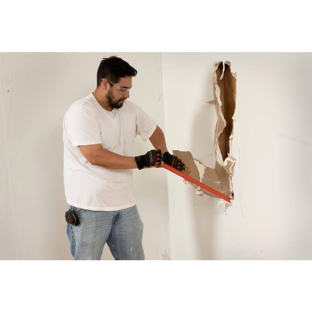 Construction worker using the straight chisel end of the Crescent PB30 30-inch steel wrecking pry bar to easily tear down drywall during an indoor heavy duty renovation project.