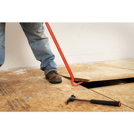Worker leveraging the gooseneck end of the Crescent PB30 30-inch I-beam steel wrecking pry bar to lift and tear down heavy wooden subfloor panels on a demolition job site.
