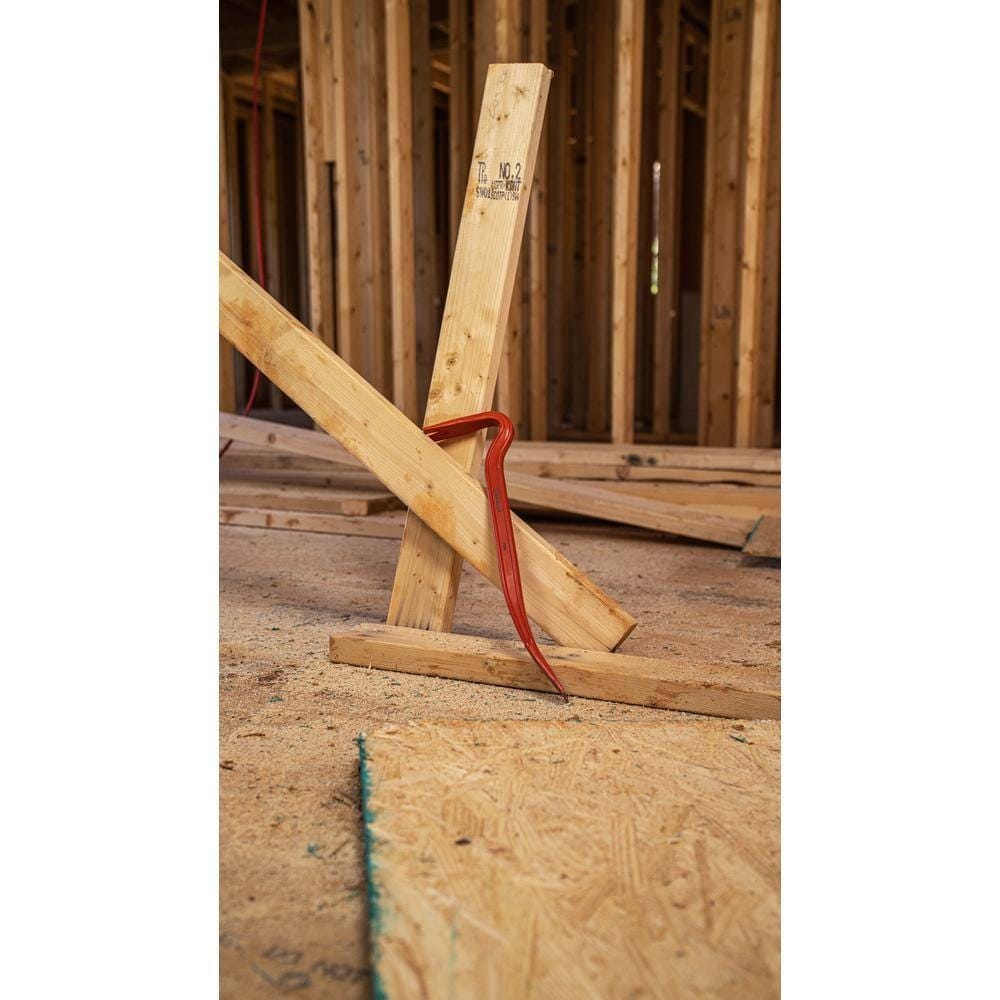 A worker using the Crescent PB36 steel wrecking bar to pry apart a vertical wooden wall stud from a base plate, demonstrating the tool's massive leverage and strength in structural demolition.
