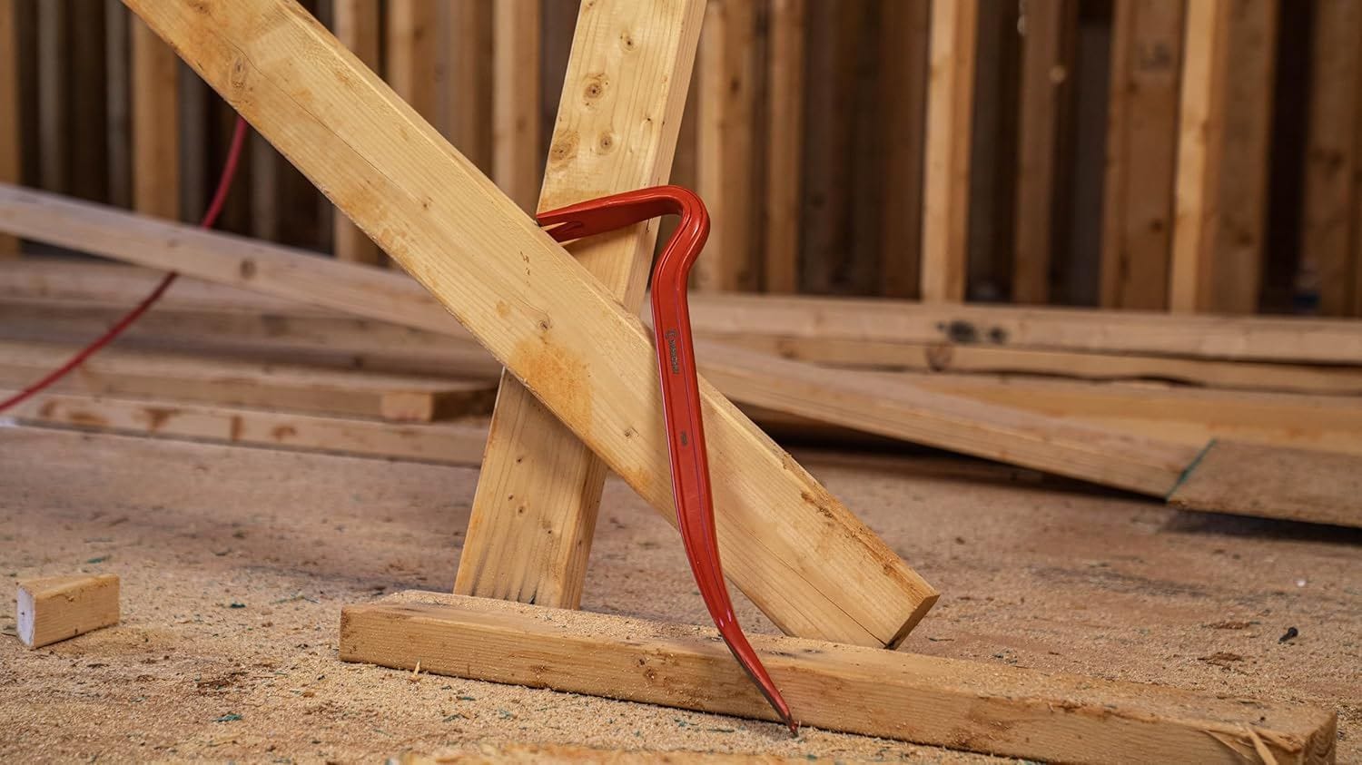 Action shot showing the Crescent PB42 wrecking bar being used to pry a wooden structural stud away from a frame, demonstrating the mechanical advantage of its length.