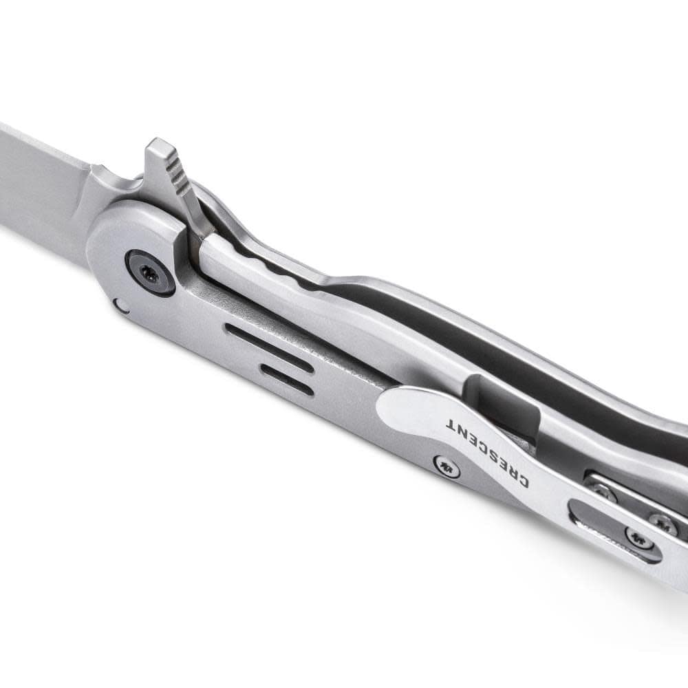 Detailed macro view focusing on the internal mechanics of the folding knife, displaying the ball-bearing pivot, smooth manual flipper tab, and the frame lock mechanism securely engaging the base of the open blade.