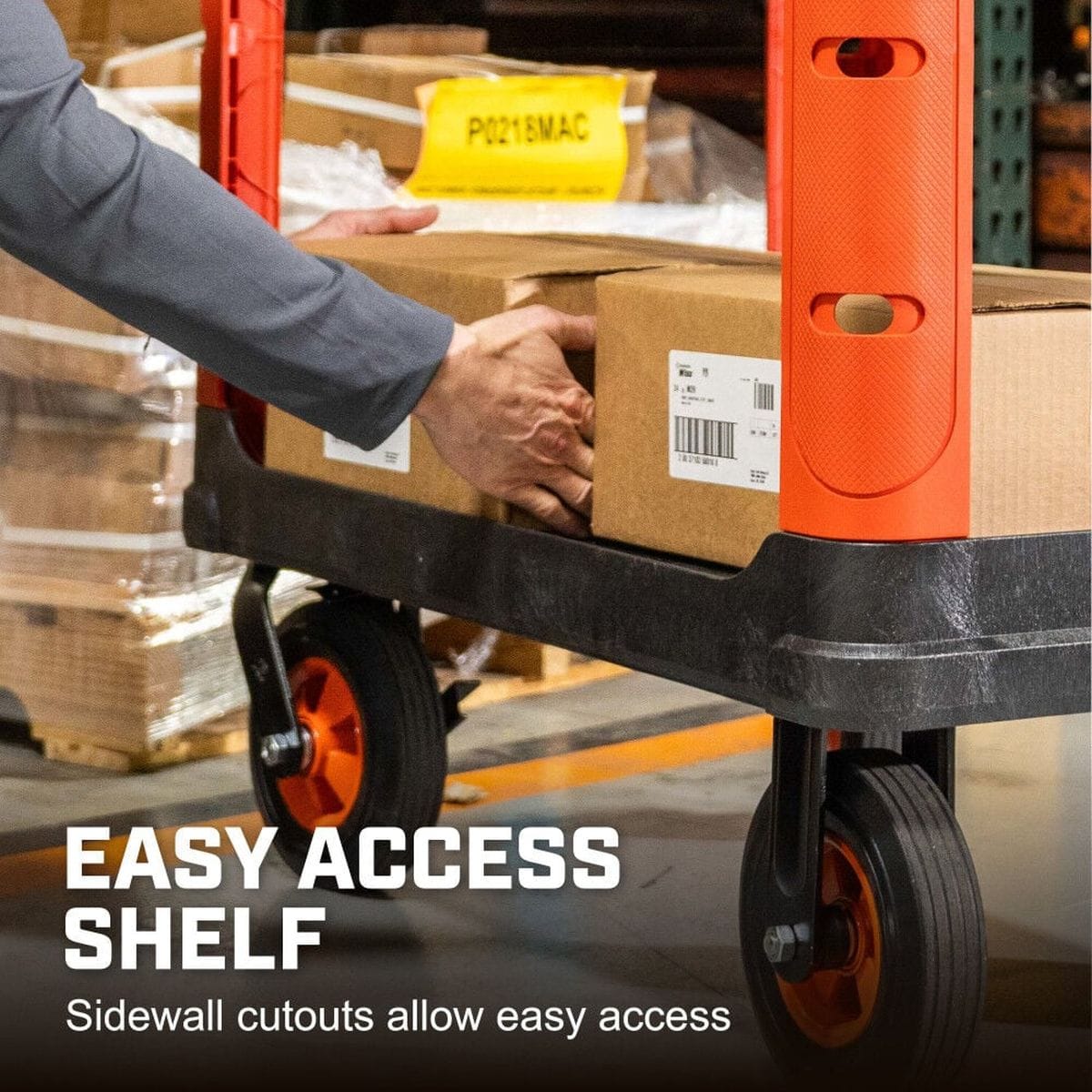 A functional demonstration highlighting the easy-access shelf design, showing a user sliding a heavy cardboard box through the ergonomic sidewall cutouts on the bottom shelf of the orange industrial utility cart.