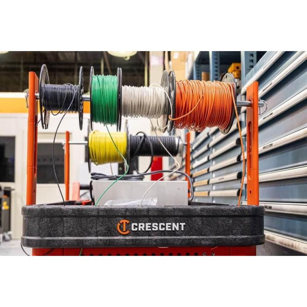 An action shot of the Crescent RAILWORKS cart being used as a mobile wire spool station in an industrial warehouse. Multiple spools of electrical wire are mounted on integrated rails above the top shelf, showcasing the cart’s utility for electrical contractors.