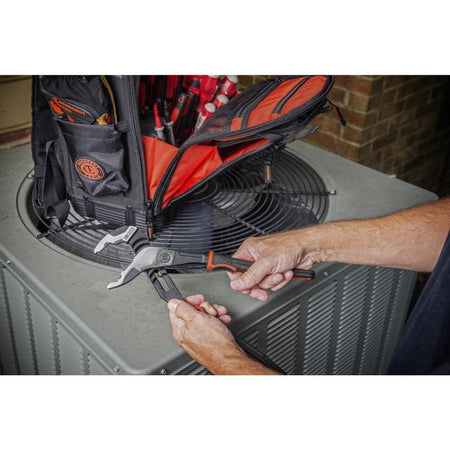 A technician holding the Crescent Z2 pliers next to an open tool bag while performing maintenance on an outdoor HVAC unit, demonstrating jobsite portability and utility.