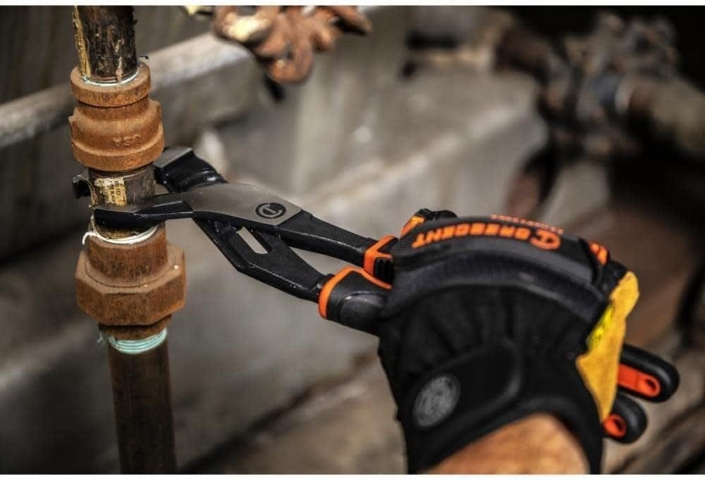 Action shot of a professional using the Crescent Z2 K9 V-jaw pliers to securely grip and turn a heavy-duty industrial pipe fitting in a confined space.