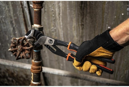 Action shot of a professional tradesman using the Crescent 12-inch Z2 pliers with a high-leverage grip to turn a rusted metal valve on an industrial pipe.