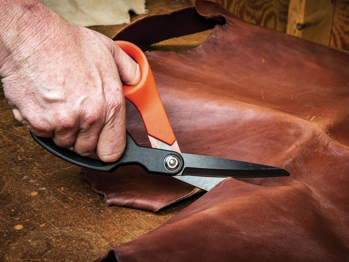 Action shot demonstrating the precision of the Crescent Wiss shears while cutting through heavy-duty rawhide leather, illustrating the superior control provided by the ergonomic handle.