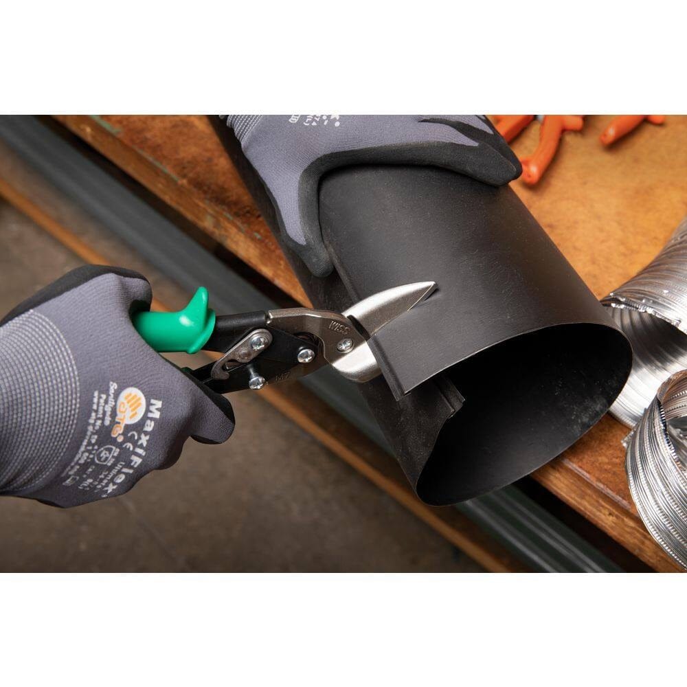 A close-up action shot of a professional technician using the Crescent Wiss M7R aviation snips to cut through black HVAC ductwork, demonstrating the 30-degree offset head for hand clearance and material flow.