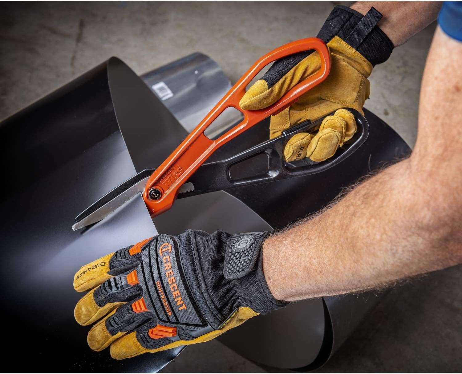 A professional HVAC technician wearing Crescent protective work gloves using the 13-inch aluminum tinner snips to precisely shear thin-gauge metal ducting material on a jobsite.