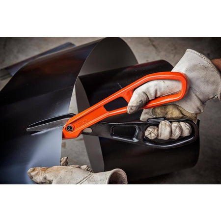 Close-up action view of a worker in heavy-duty leather safety gloves using the Crescent Wiss straight-cut metal shears to navigate a precise line through a roll of sheet metal.