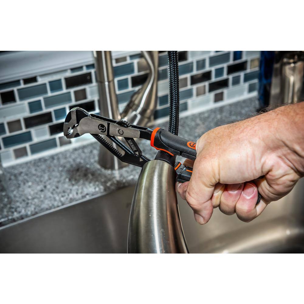 A detailed close-up lifestyle shot of a technician using the one-handed automatic adjusting pliers to grip and steady a curved chrome bathroom plumbing fixture above a steel sink.